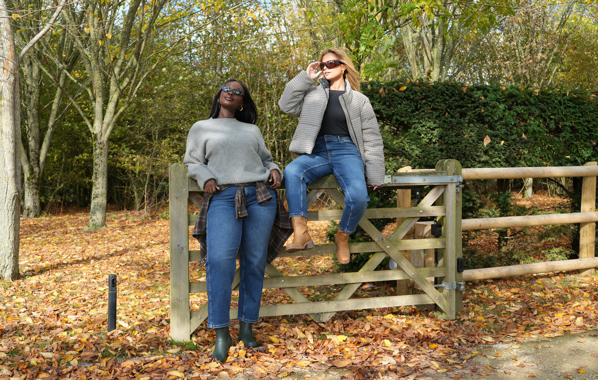 Two women in Ambela Stretch Relaxed Mom jeans at a wooden gate in autumn
